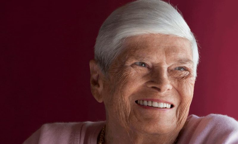 Portrait d'une vieille dame aux cheveux blancs qui sourit.