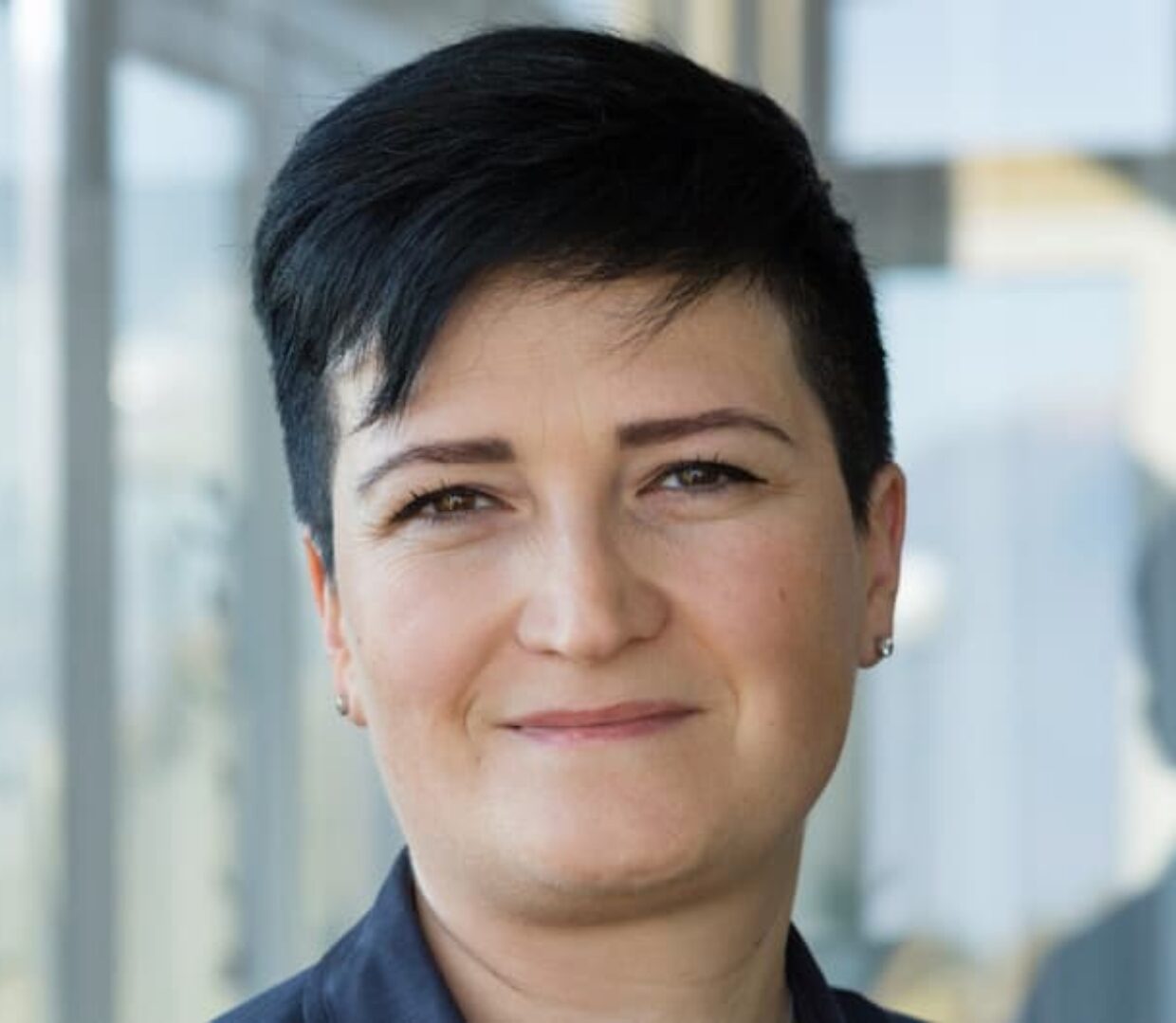 Portrait einer motivierten diplomierten Pflegefachfrau mit kurzen schwarzen Haaren.