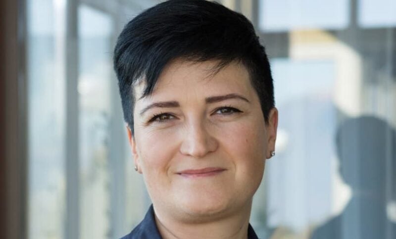 Portrait einer motivierten diplomierten Pflegefachfrau mit kurzen schwarzen Haaren.